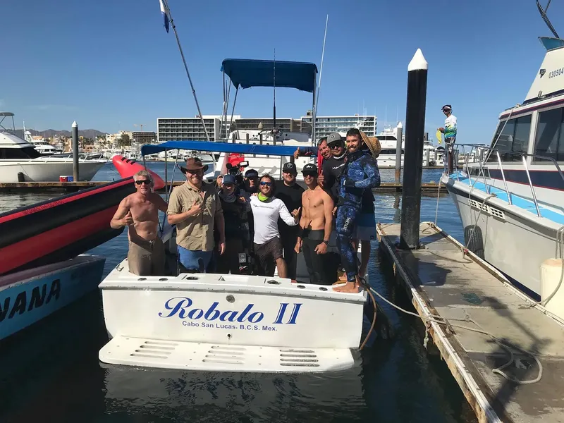 Groupe de plongeurs souriants posant sur un bateau dans un port ensoleillé