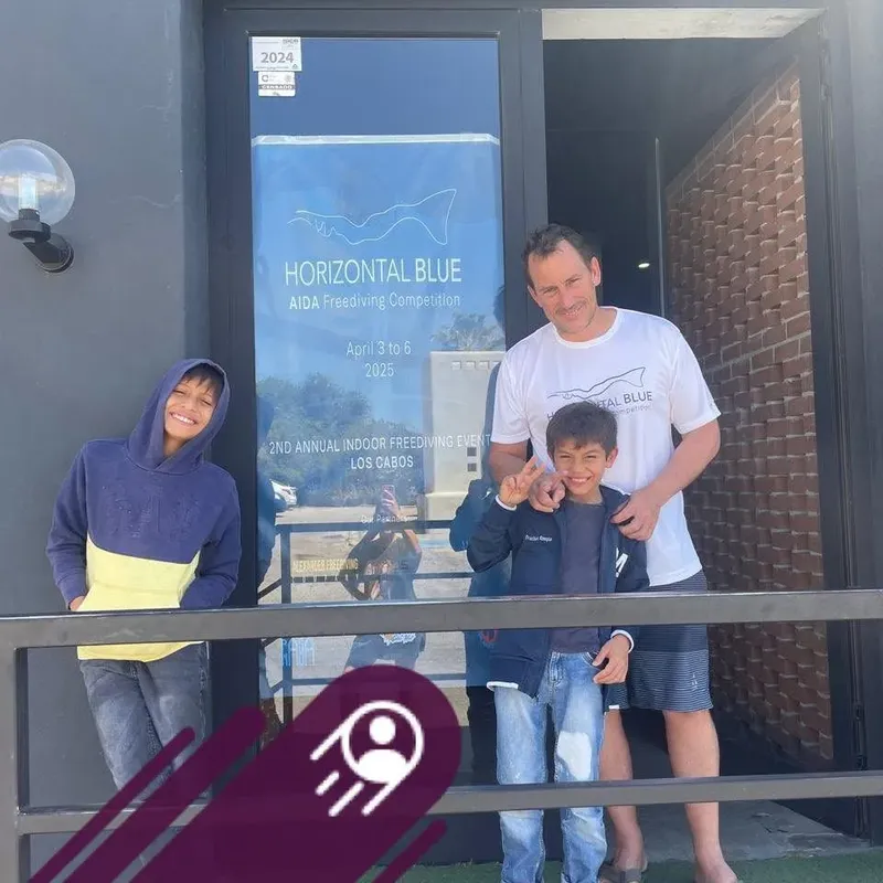Deux enfants et un homme devant une affiche de compétition d'apnée