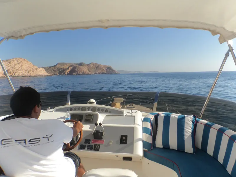 Homme conduisant un bateau de plongée en mer, vue depuis l'intérieur