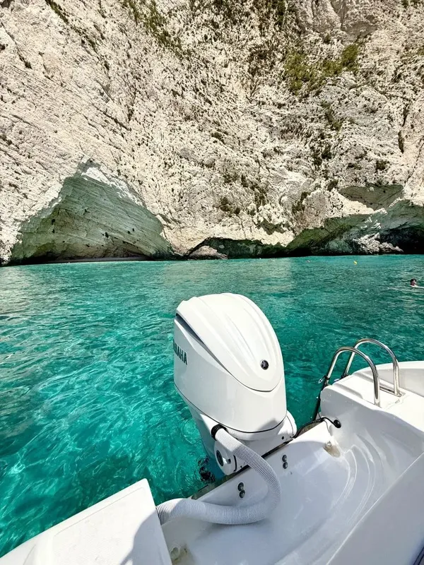 Bateau de plaisance naviguant sur une eau turquoise près de falaises blanches