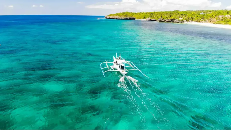 Bateau de pêche traditionnel filant sur une mer turquoise et claire