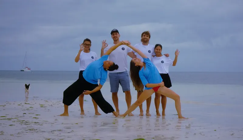 Groupe de personnes souriantes faisant des poses sur une plage