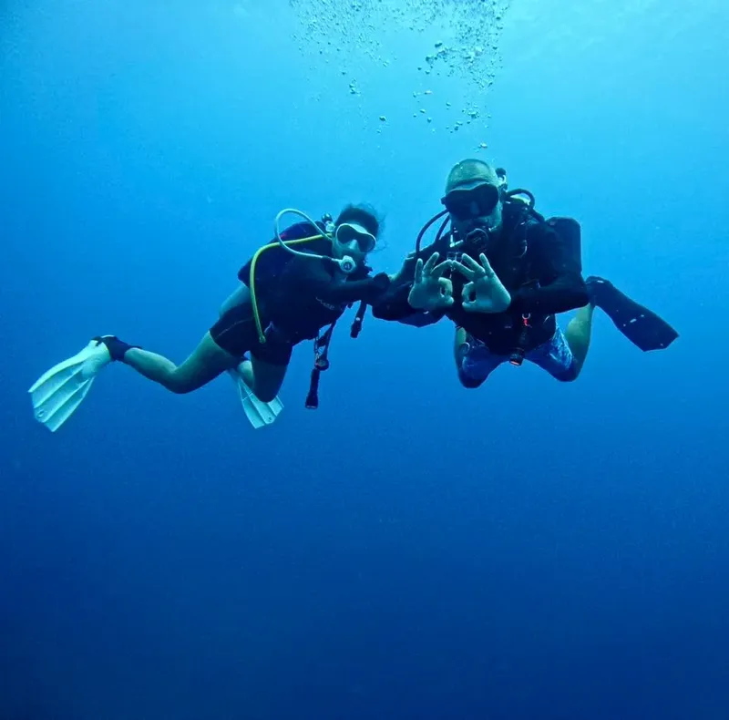Deux plongeurs communiquent sous l'eau dans une mer bleue claire
