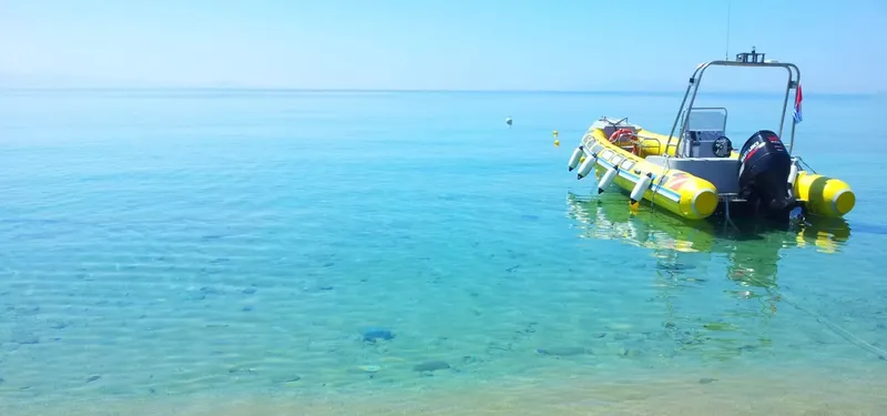 Bateau de plongée jaune et bleu amarré dans une eau turquoise claire