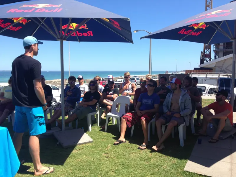 Groupe de personnes assis sur des chaises sous des parasols Red Bull