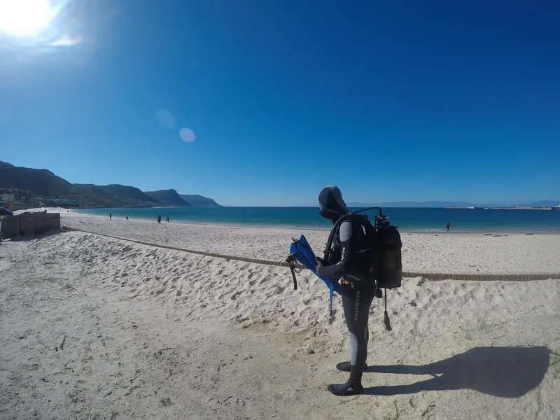Plongeur équipé sur une plage de sable avec une mer calme