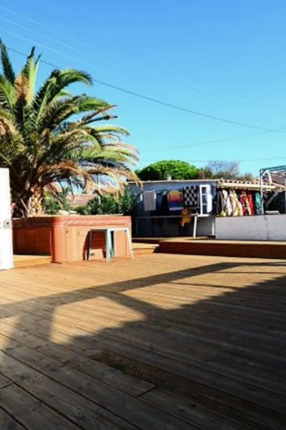 Terrasse en bois devant un bâtiment avec des combinaisons de plongée