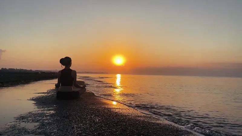 Silhouette d'une personne en méditation au lever du soleil sur la plage