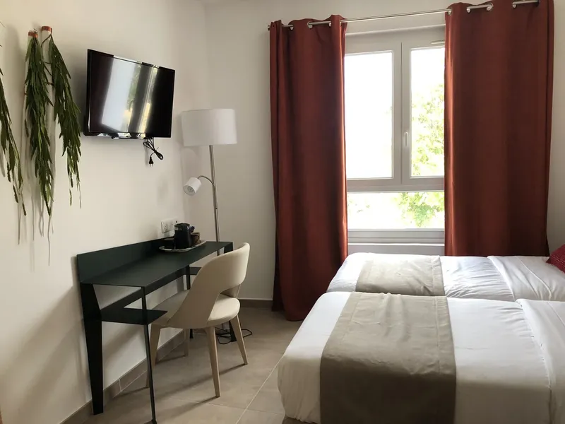 Chambre d'hôtel avec deux lits simples, bureau et télévision murale