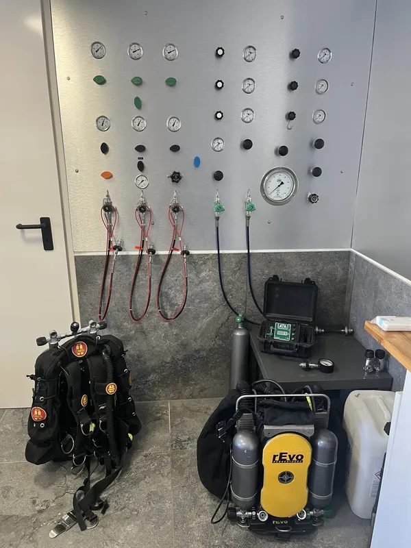 Mur d'équipement de plongée avec bouteilles, manomètres et compresseur jaune