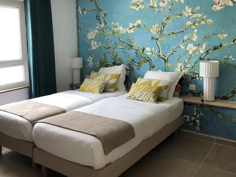 Chambre d'hôtel avec deux lits simples et un décor floral mural