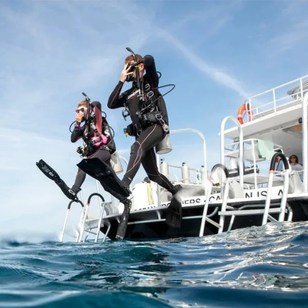 Deux plongeurs sautent d'un bateau de plongée en pleine mer