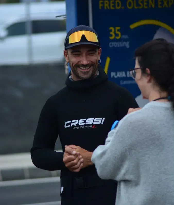 Deux personnes souriantes discutent, l'une porte une combinaison de plongée