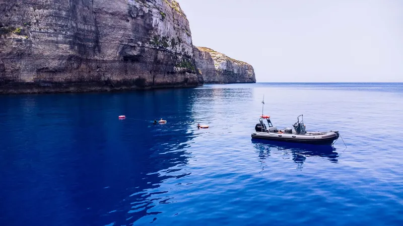 Plongeurs en surface près d'un bateau et d'une falaise rocheuse