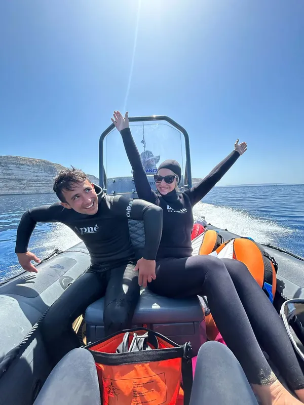 Deux plongeurs enthousiastes lèvent les bras sur un bateau pneumatique en mer