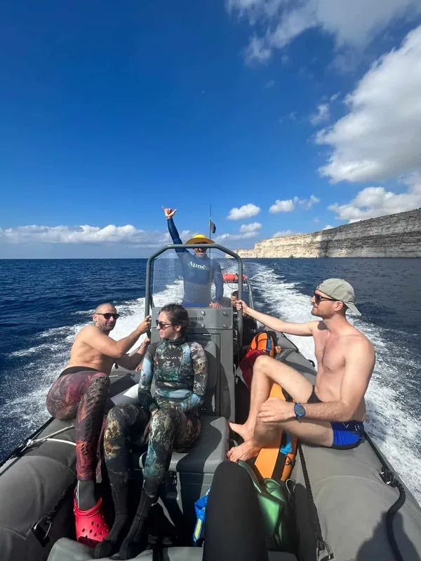 Quatre personnes à bord d'un semi-rigide en mer, direction falaise