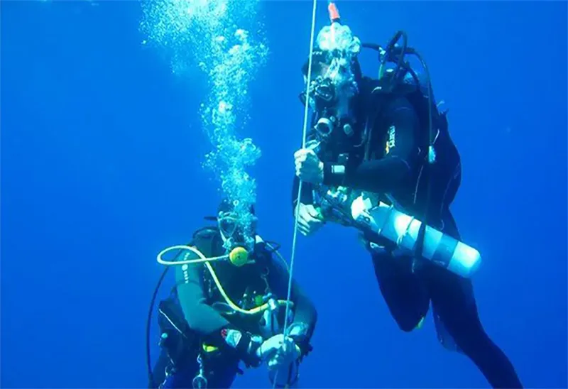 Deux plongeurs en combinaison explorent les profondeurs bleues sous-marines