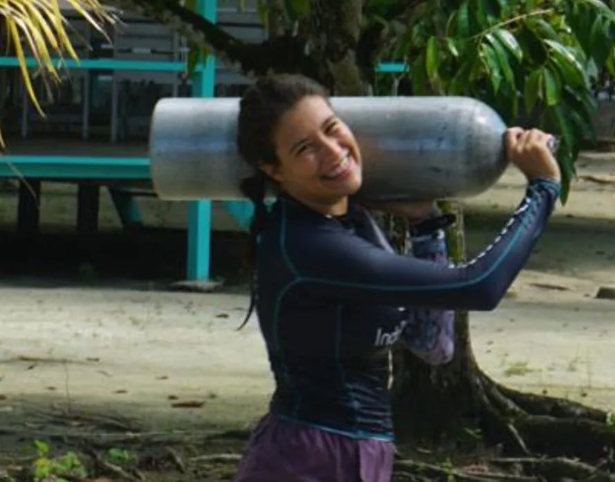 Jeune femme souriante portant une bouteille de plongée sur la tête