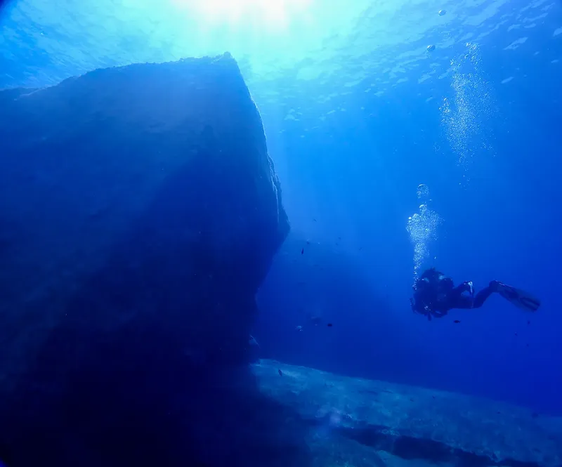 Plongeur explorant une épave sous-marine dans une eau bleue claire