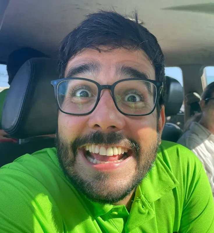Portrait d'un homme souriant avec des lunettes, regardant l'appareil photo