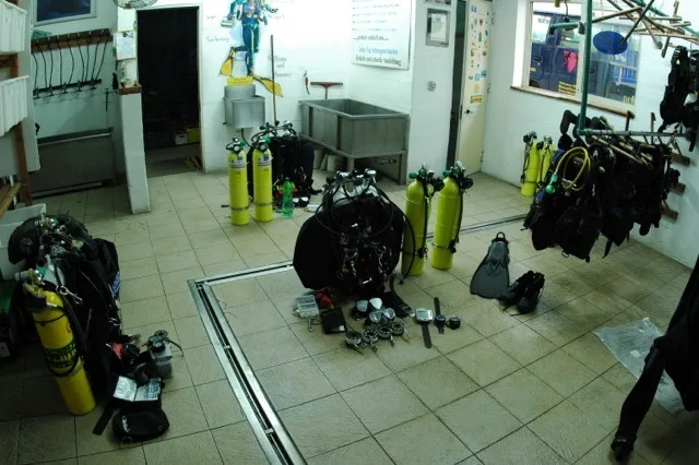 Salle de préparation plongée avec équipements, bouteilles et bac de rinçage