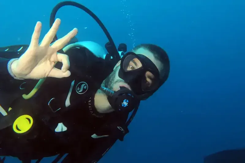 Plongeur souriant avec signe OK, équipé en milieu aquatique bleu