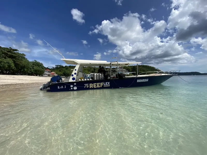 Bateau de plongée bleu et blanc amarré dans une eau turquoise claire