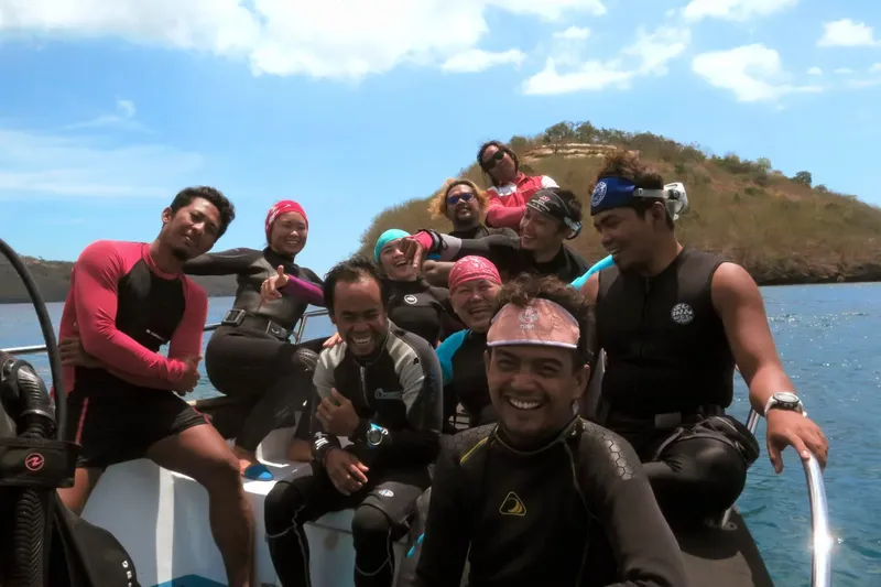 Groupe de personnes souriantes en combinaison de plongée sur un bateau