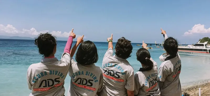 Quatre personnes pointent vers un bateau en mer sous un ciel bleu