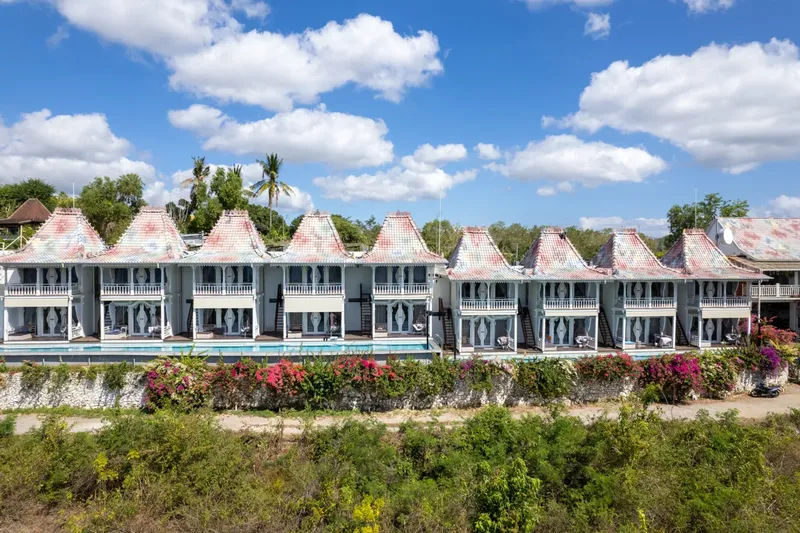 Vue d'ensemble d'une série de bungalows blancs avec piscine et végétation tropicale