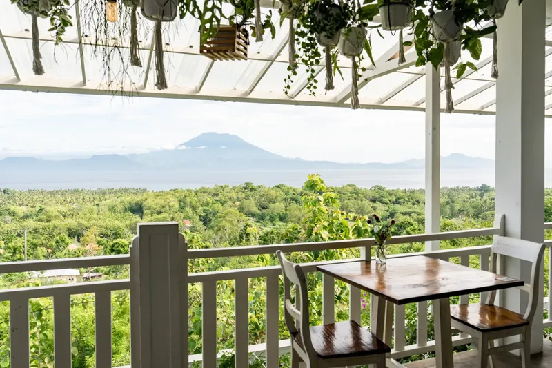 Terrasse ombragée avec vue sur la mer, la végétation et un volcan
