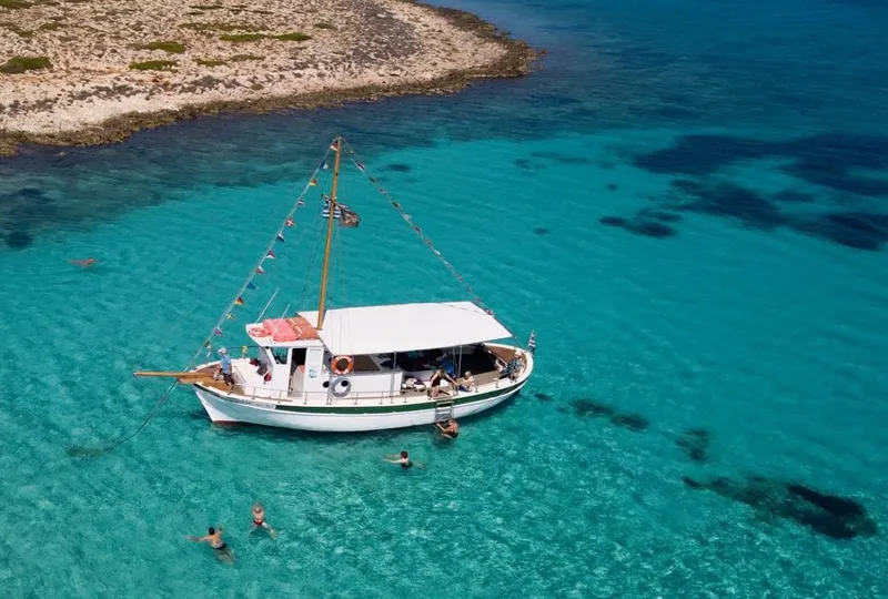 Bateau de plaisance amarré dans une eau turquoise avec des baigneurs