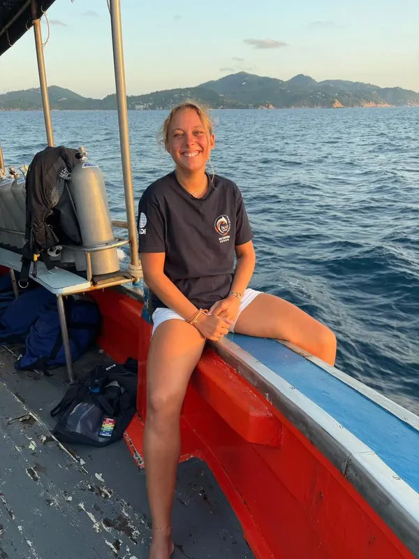 Jeune femme souriante assise sur un bateau de plongée en mer
