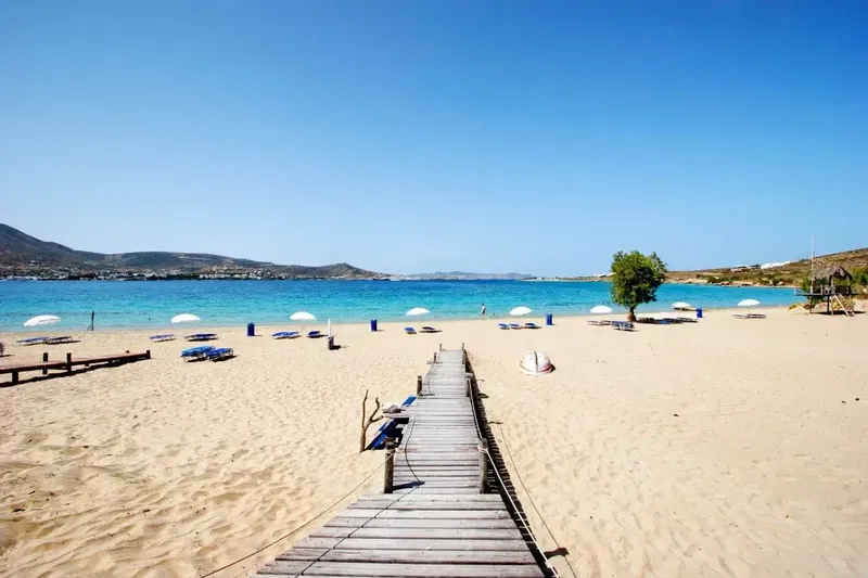 Plage de sable fin avec une passerelle en bois et mer turquoise