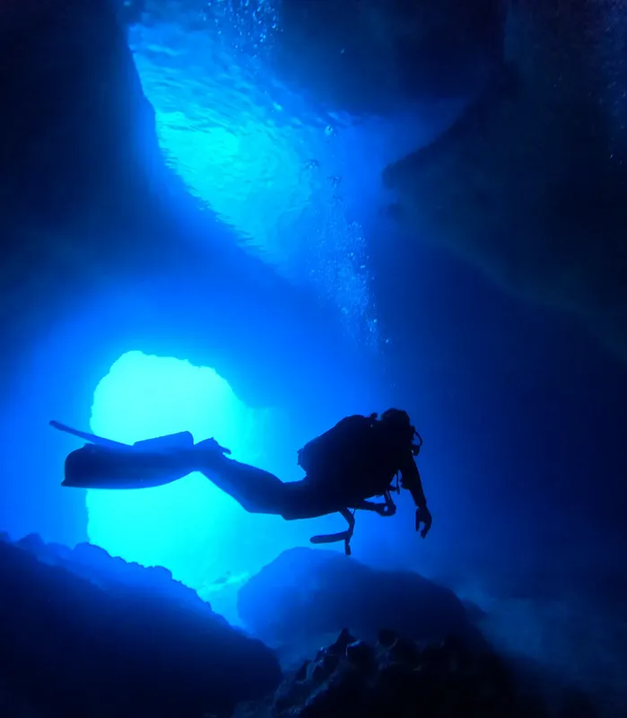 Plongeur silhouette explore une grotte sous-marine éclairée par le soleil