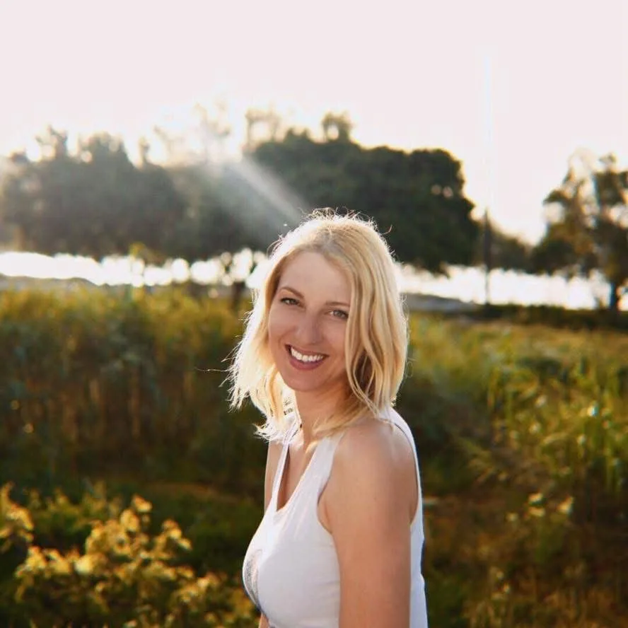 Portrait d'une jeune femme souriante, cheveux blonds, en extérieur