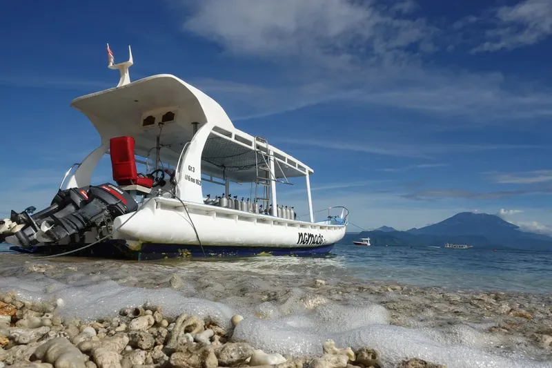 Bateau de plongée blanc échoué sur une plage de galets et sable