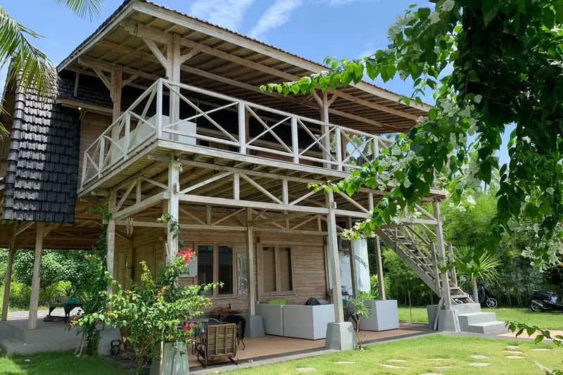 Bâtiment en bois sur pilotis avec terrasse et végétation luxuriante