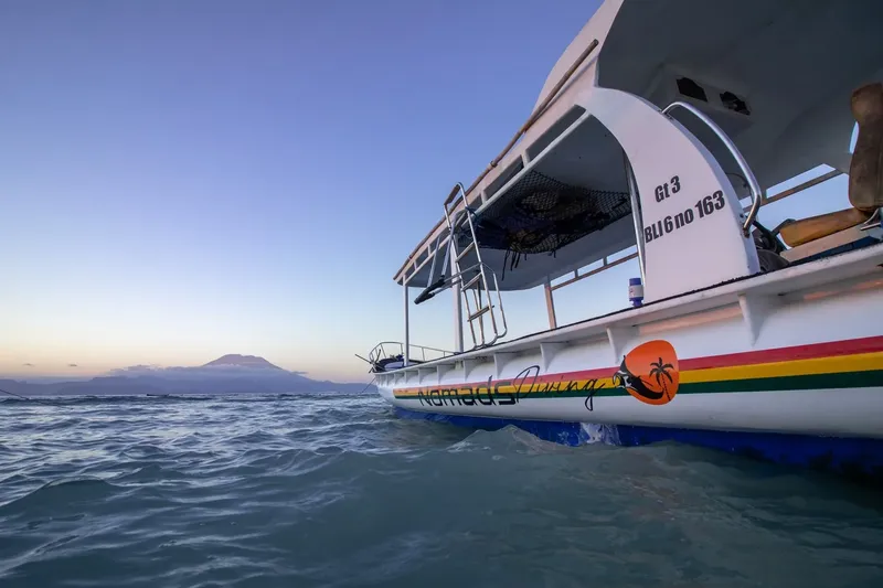 Bateau de plongée blanc et coloré sur l'eau calme au lever du soleil