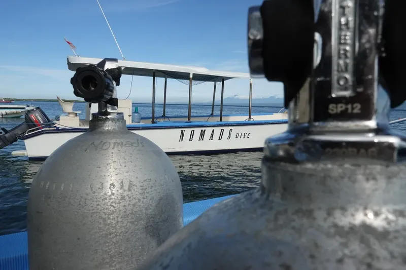 Bouteilles de plongée au premier plan, bateau de plongée en arrière-plan