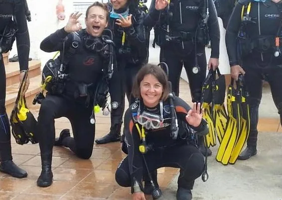 Groupe de plongeurs souriants équipés prêts pour une sortie en mer
