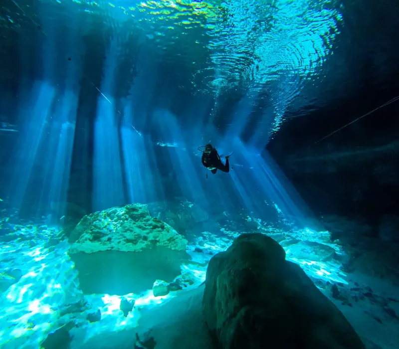 Plongeur explorant une grotte sous-marine éclairée par des rayons de soleil