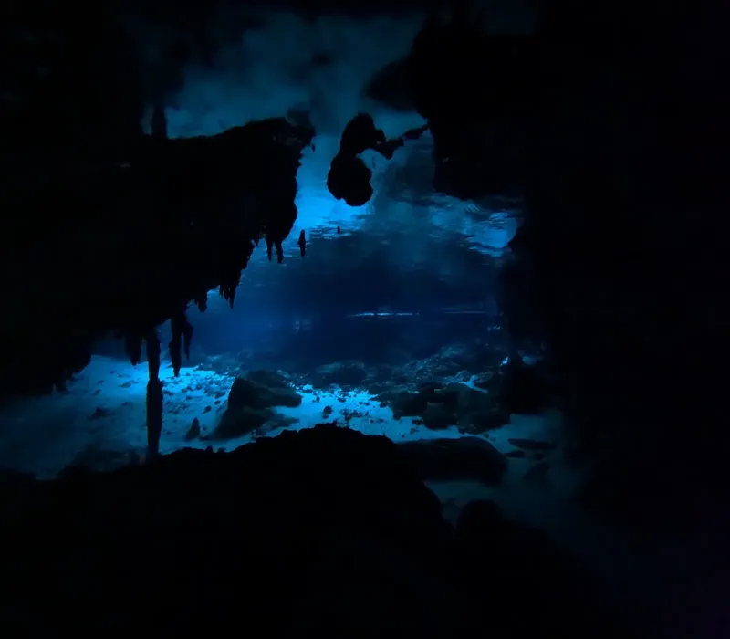 Grotte sous-marine sombre avec des formations rocheuses et lumière diffuse