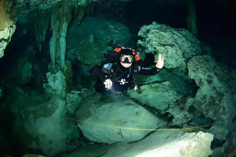 Plongeur explore une grotte sous-marine avec stalactites et rochers