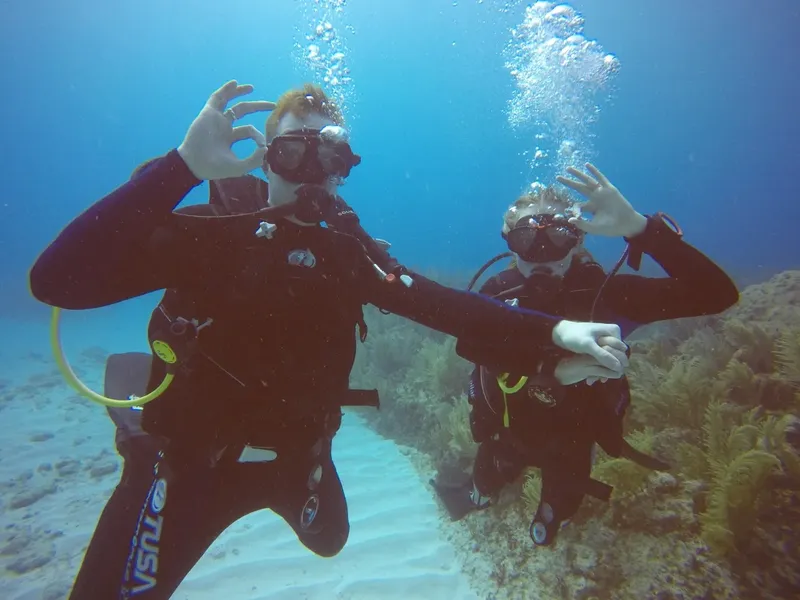 Deux plongeurs souriants font un signe OK sous l'eau