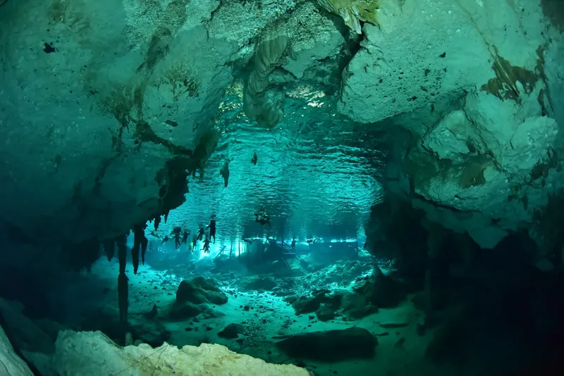 Plongeurs explorant une grotte sous-marine illuminée par la lumière du soleil