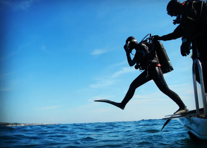 Plongeur s'apprête à sauter d'un bateau en combinaison complète