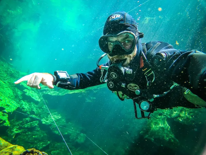 Plongeur souriant pointant vers l'avant dans une eau claire et verte