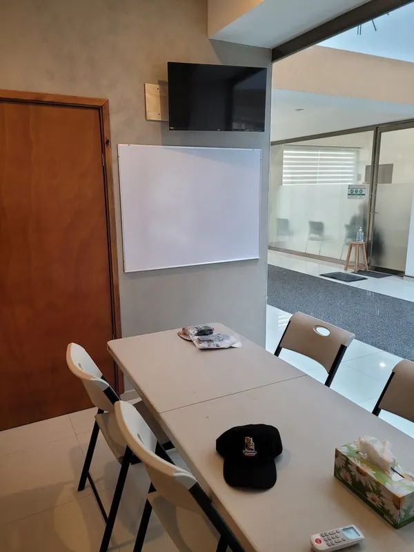 Salle de cours avec tableau blanc, table, chaises et une casquette