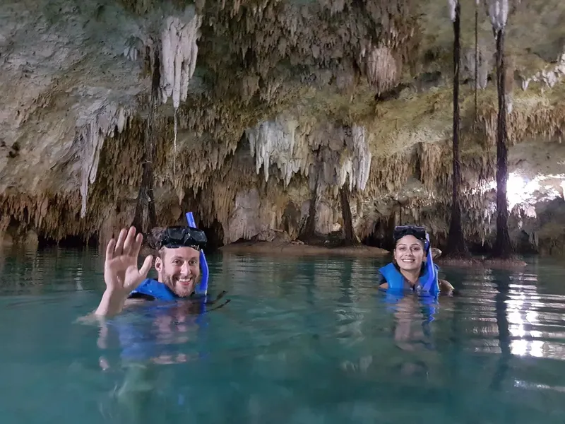 Deux personnes souriantes avec masque et tuba dans une grotte aquatique